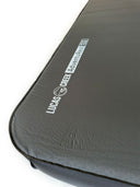 Close-up view of the corner of a black sleeping pad labeled "Lucas Creek Adventure Rest 132" on the surface.